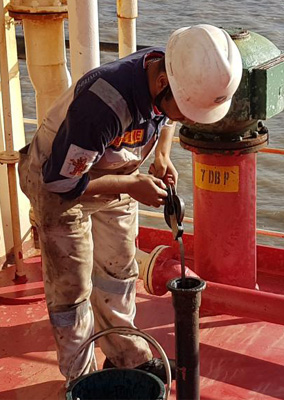 Surveyor taking a bunker sample aboard a vessel